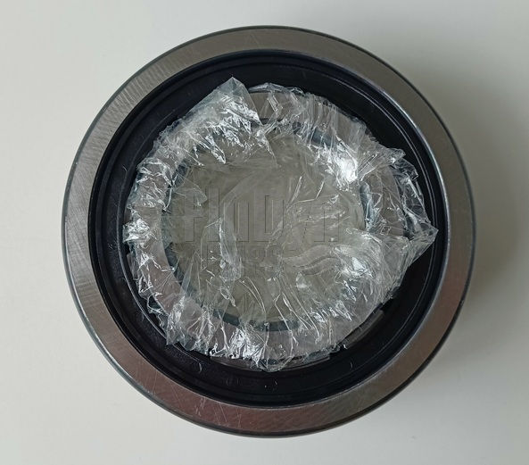 This is a photograph of a metal roller bearing against a neutral white background, taken from above. The moving part in the centre is wrapped in plastic film.